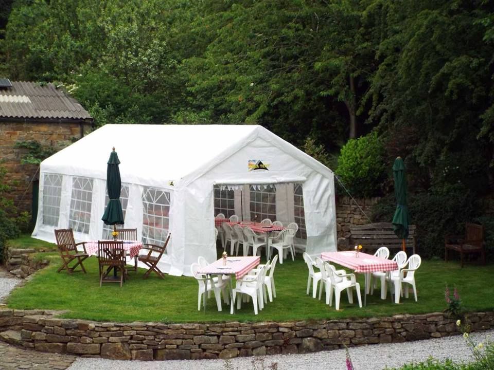 A garden party marquee with tables and chairs inside and infront of it