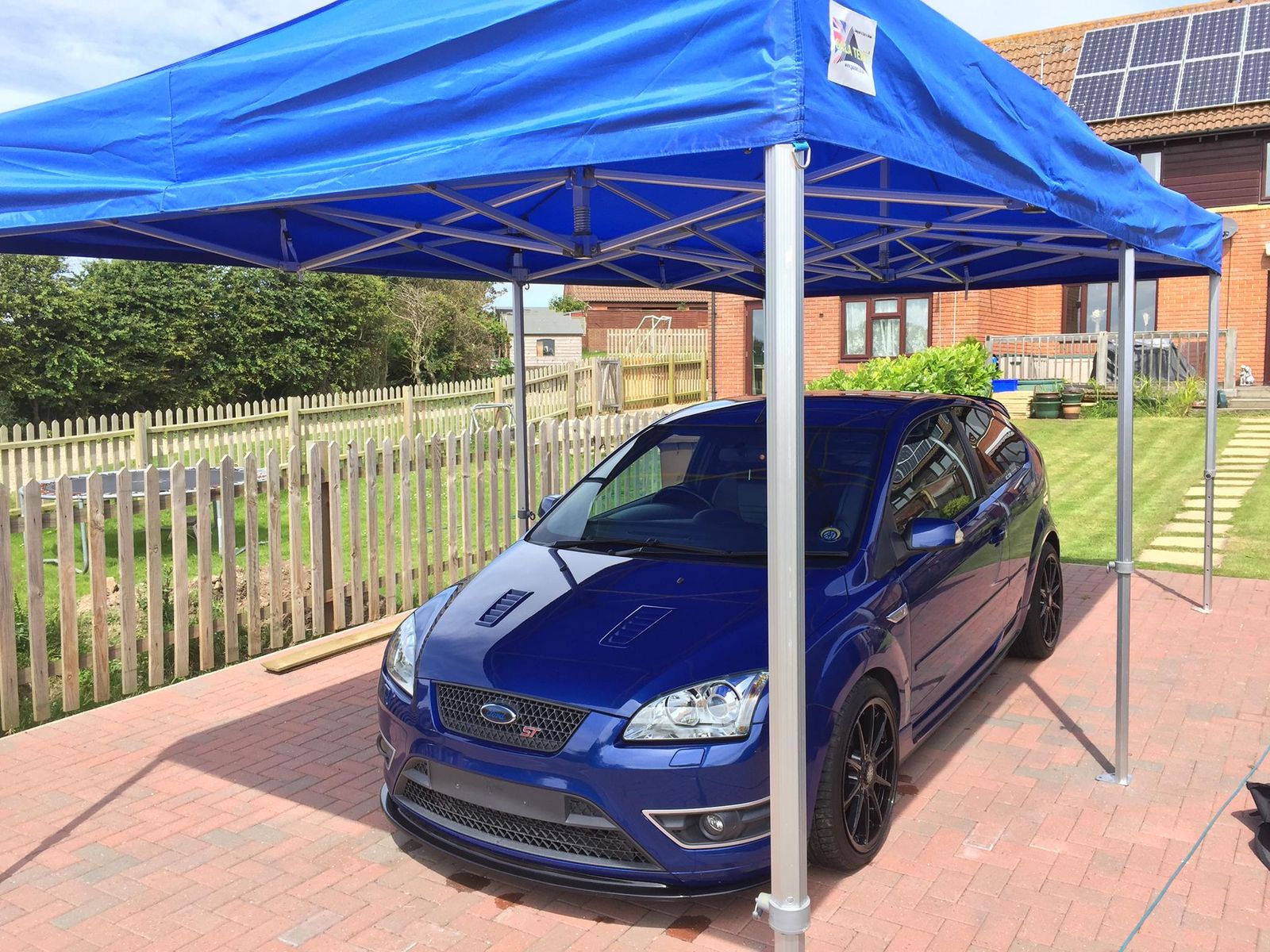 A blue valeting gazebo on a driveway