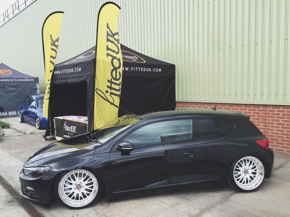 Custom Printed Gala Shade Gazebo with yellow printed feather flags next to a black car