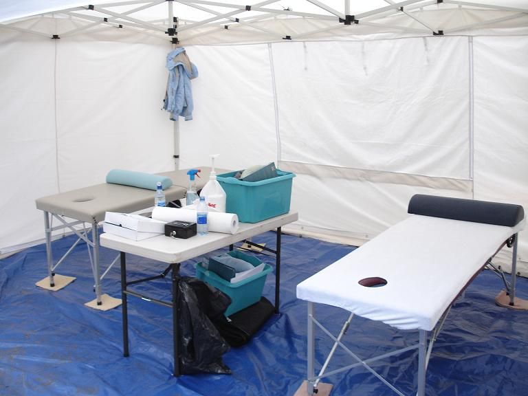 An interior view of a white gazebo containing sports therapy benches and equipment