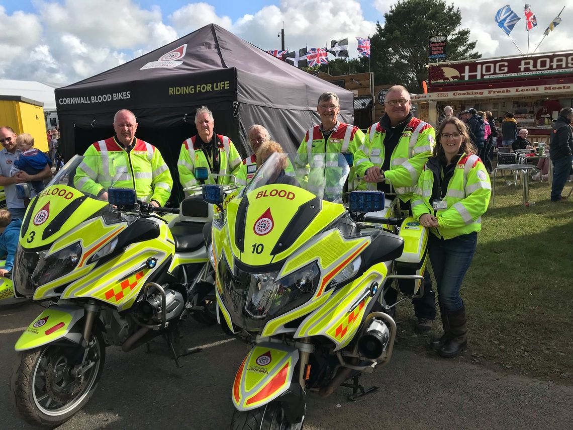 A printed gazebo in the middleground behind a group of Emergency Support workers and their motorcycles