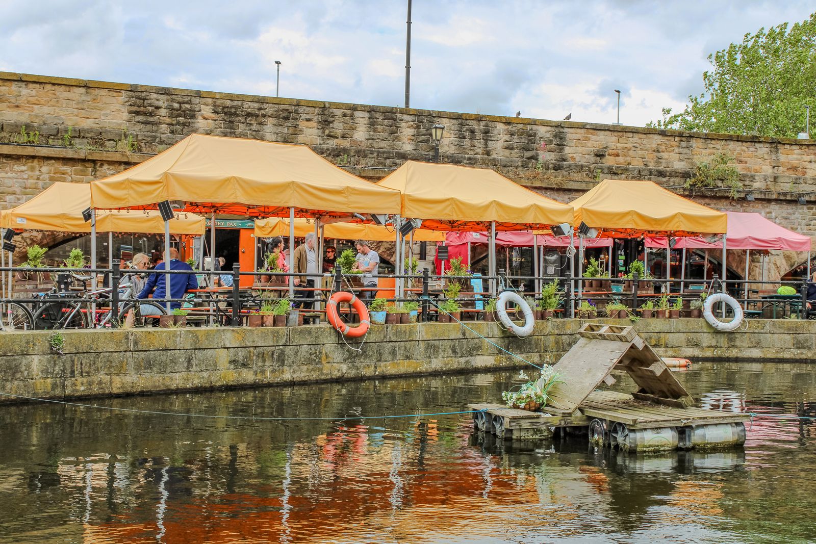 A series of orange pop up gazebos beside a canal in Sheffield