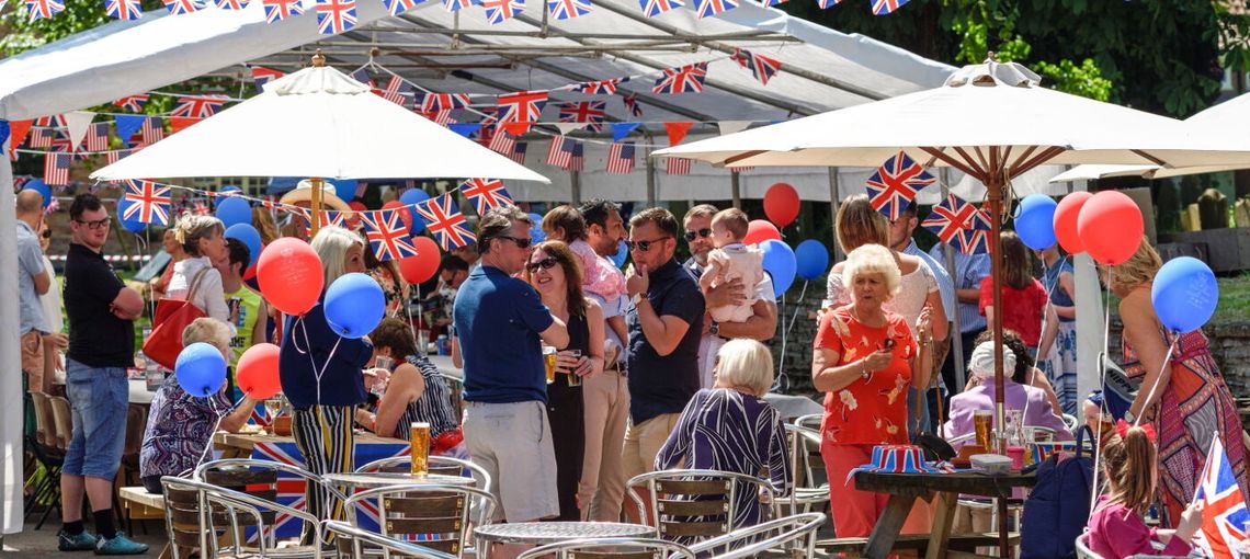 A busy street party with people surrounded by bunting