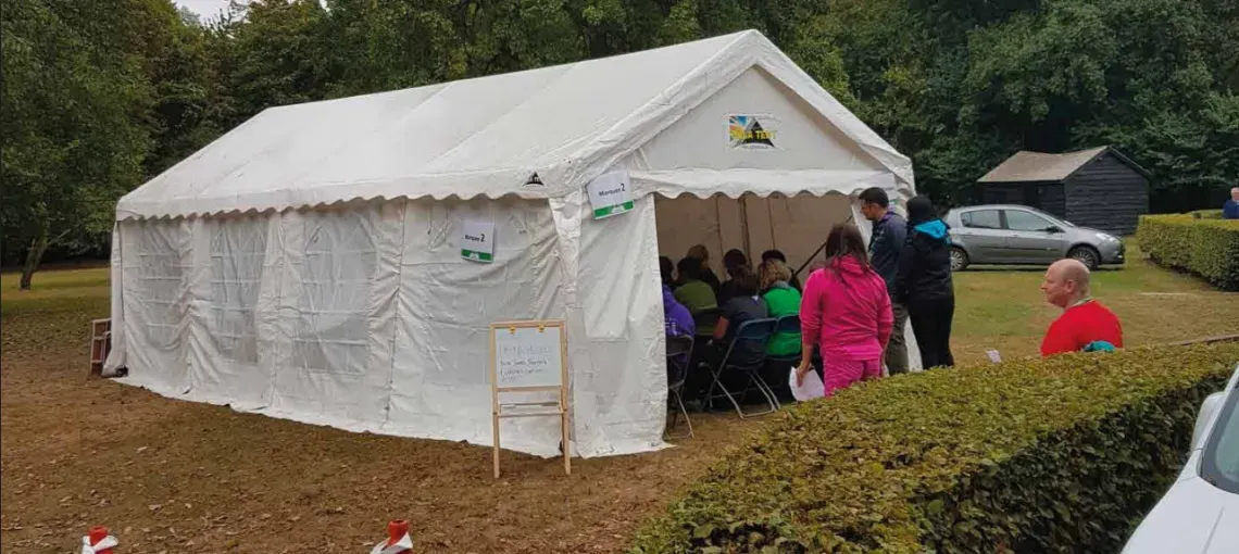 A large white marquee at a scouting event, filled with people