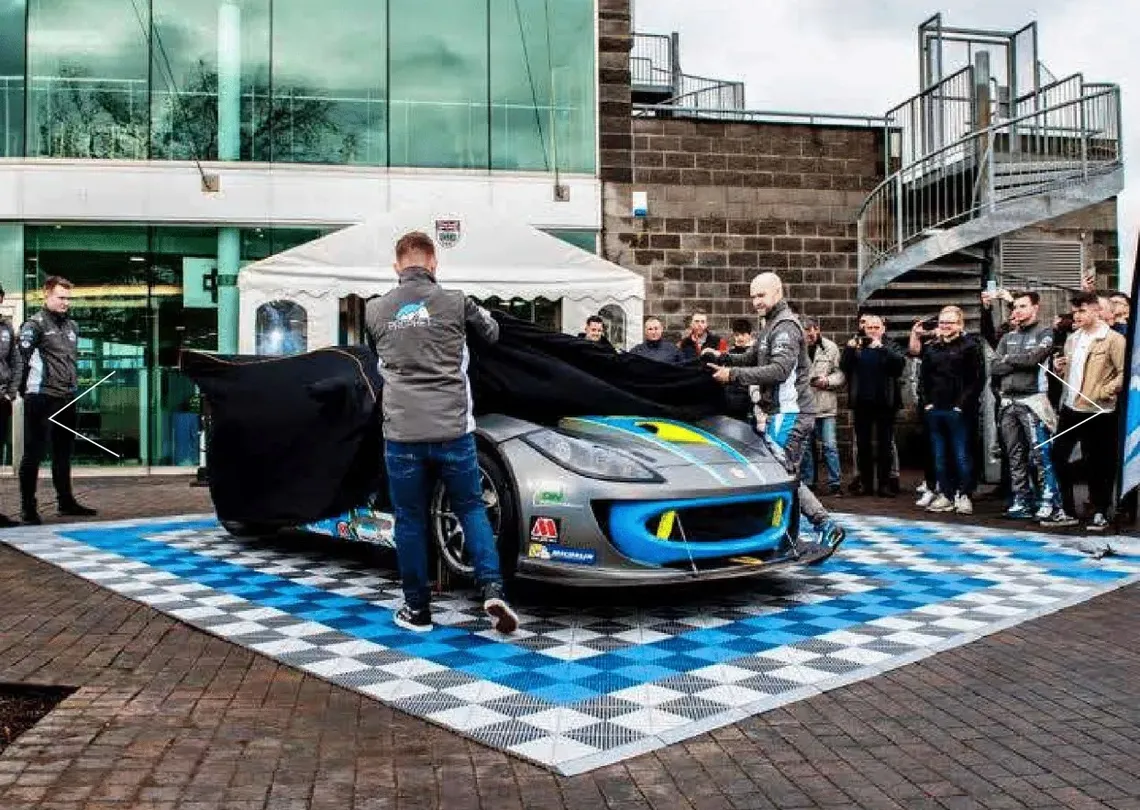 A race car being unveiled on silver and blue floor tiles