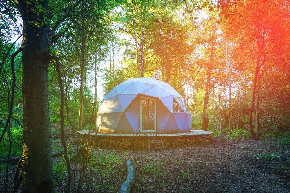 A glamping dome in a forest, the sunshine causes flare on the lens