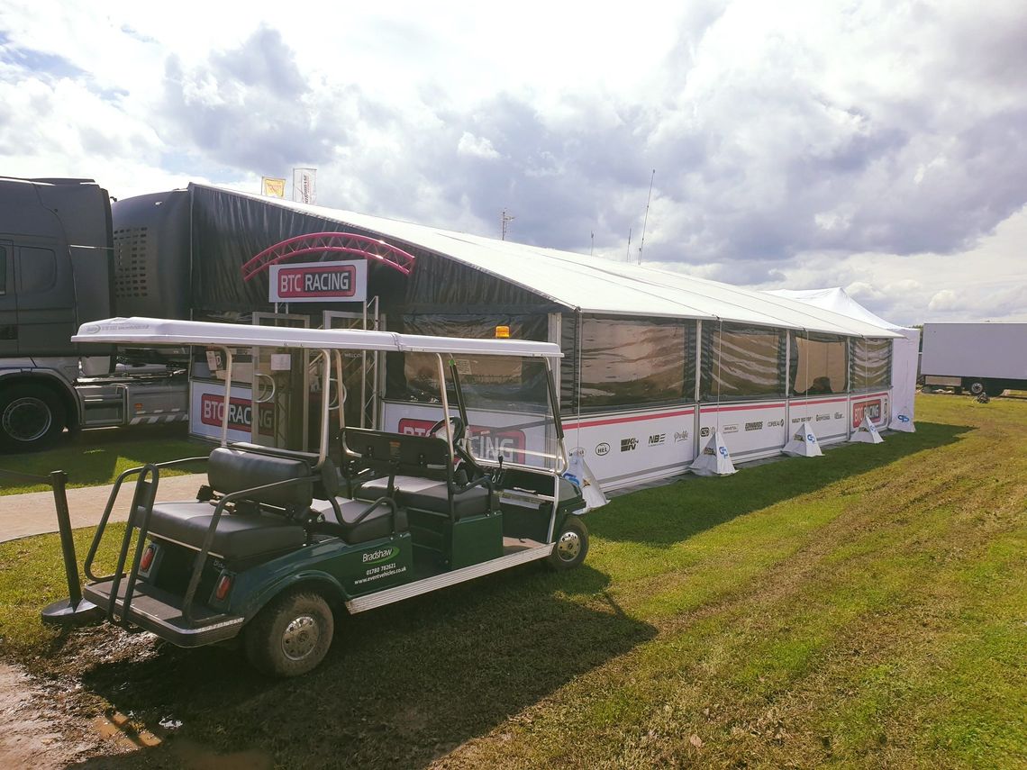 A hospitality tent at a motorsport event, with effective weights along the length. A golf buggy sits in front of it.