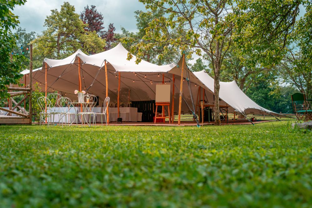 An elegant stretch tent in green space, set up for a wedding