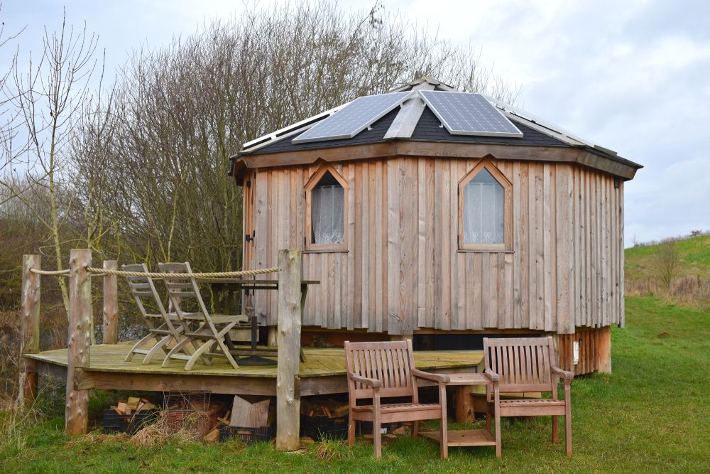 A wooden glamping pod with solar panels on the roof