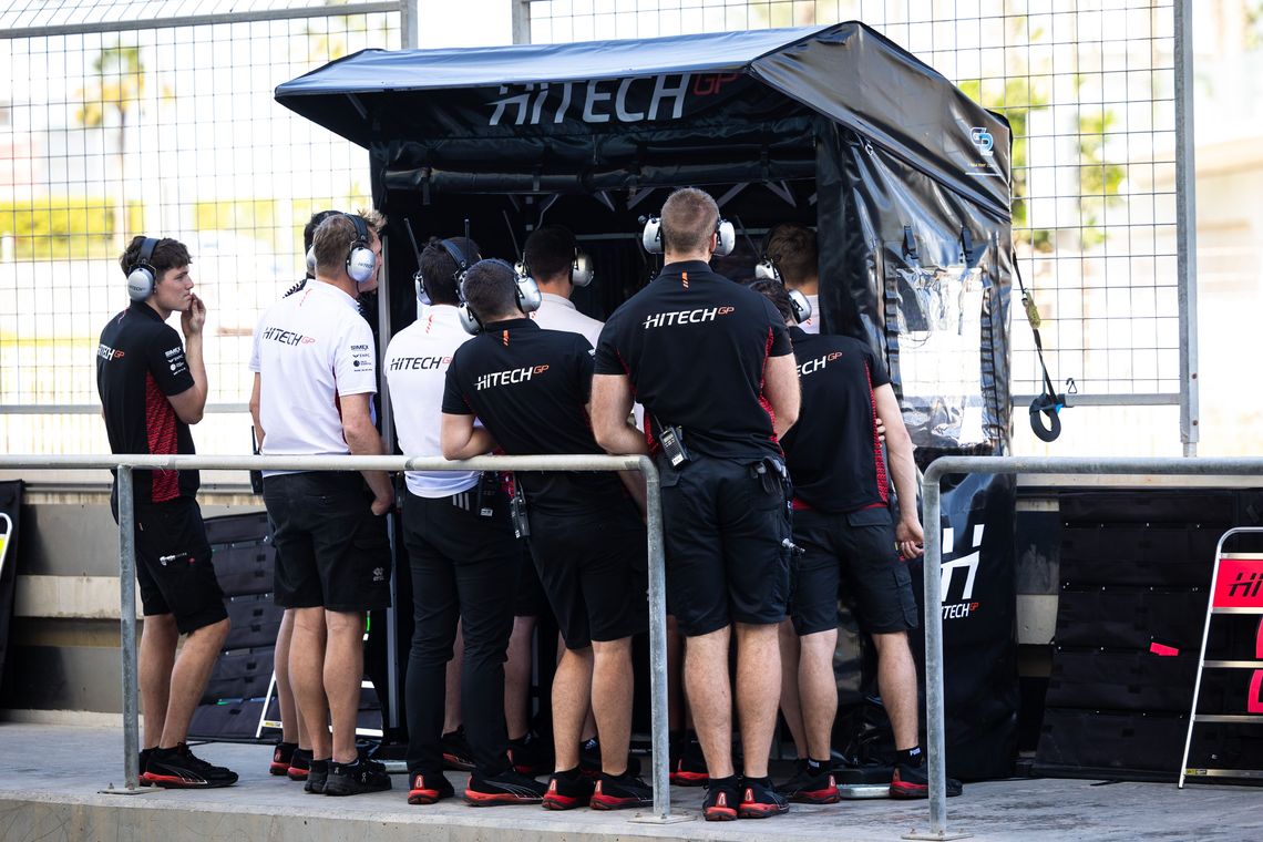 A race team beneath a pop up pit perch on a racing pit lane